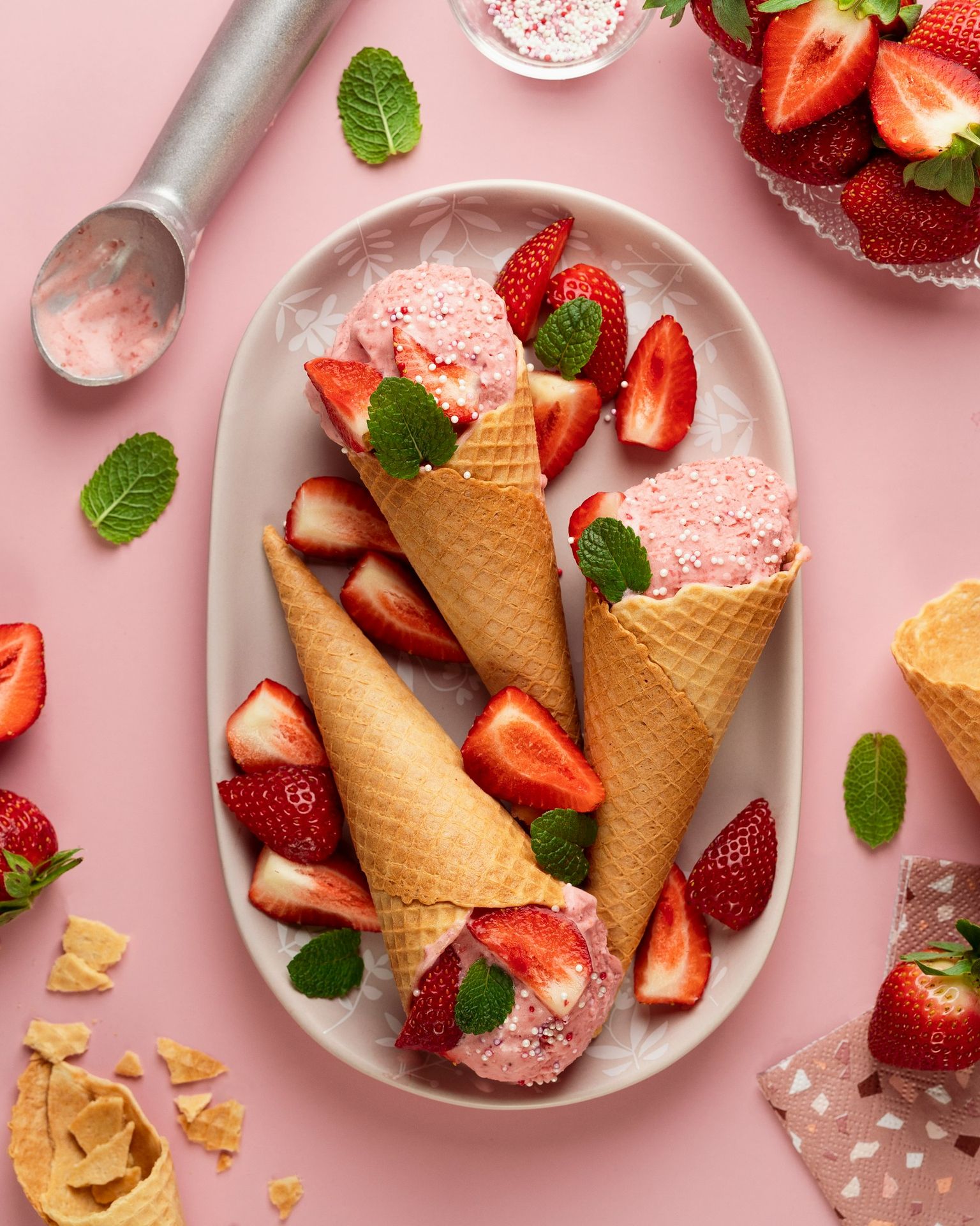 Three ice cream cones with strawberries on a plate